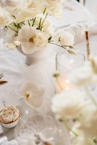 gedeckter wei&szlig;er Tisch mit wei&szlig;em Gef&auml;&szlig; mit Fu&szlig; als Centerpiece gef&uuml;llt mit wei&szlig;en Rosen